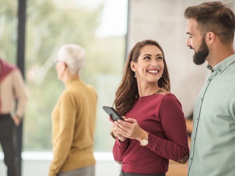 Representative holding a phone while talking with two customers in a bright lobby